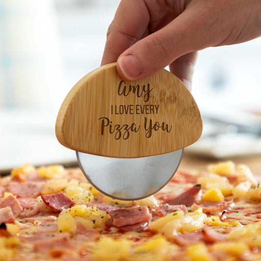 Wooden pizza cutter with engraved personalised name and 'I love every pizza you' message over a pizza.