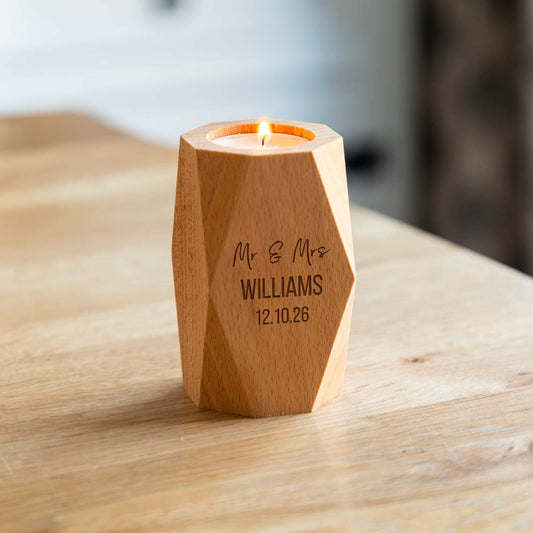 Geometric wooden candle holder engraved Mr & Mrs with a personalised surname and wedding date, holding a lit tealight on a wooden table.