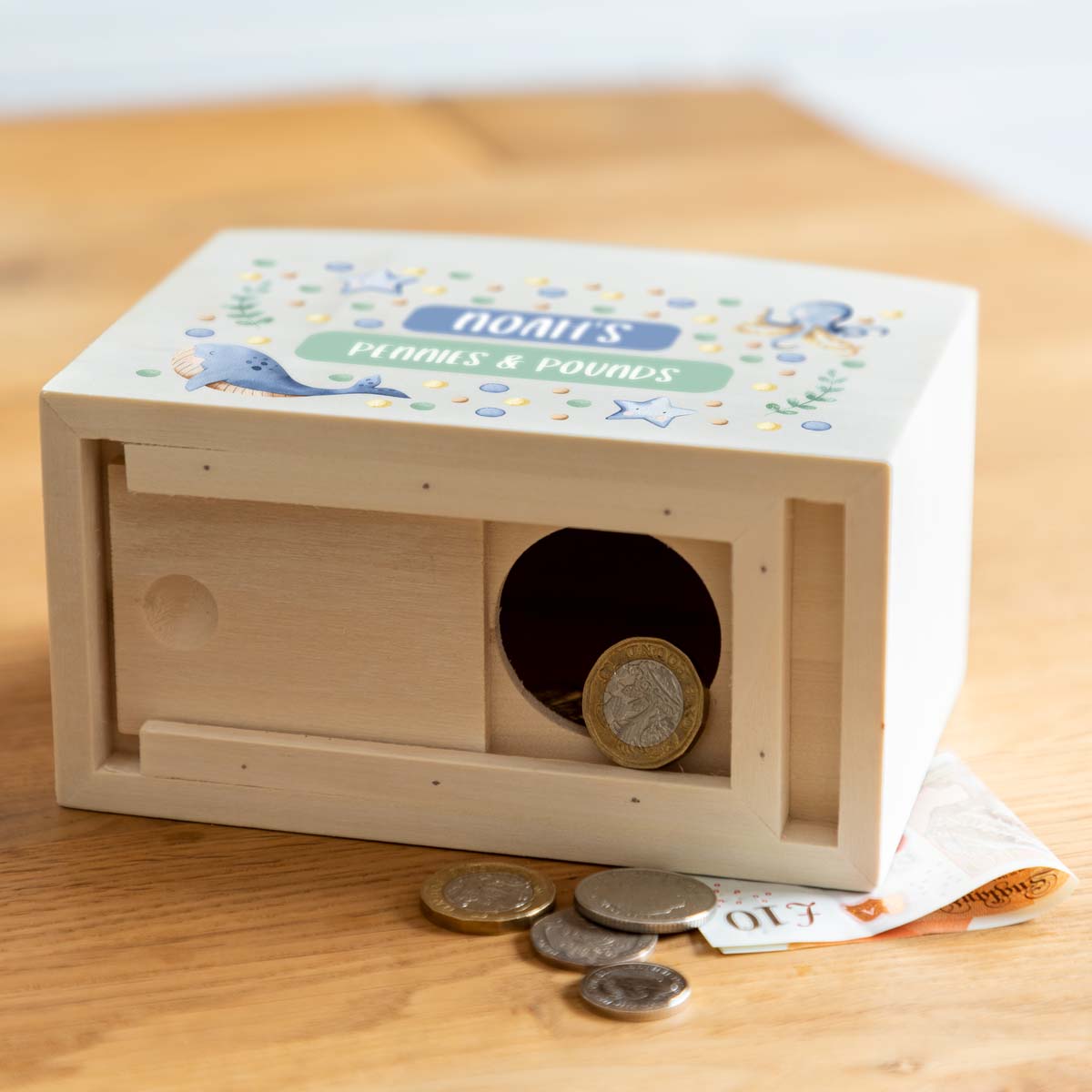 Wooden money box with a sliding opening on the bottom to access the money.
