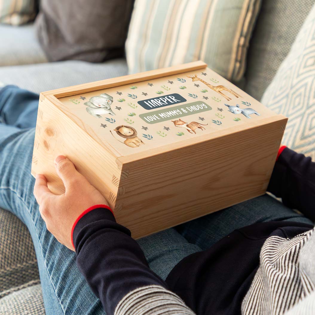 Person holding a wooden keepsake box with jungle animal illustrations and personalised text.