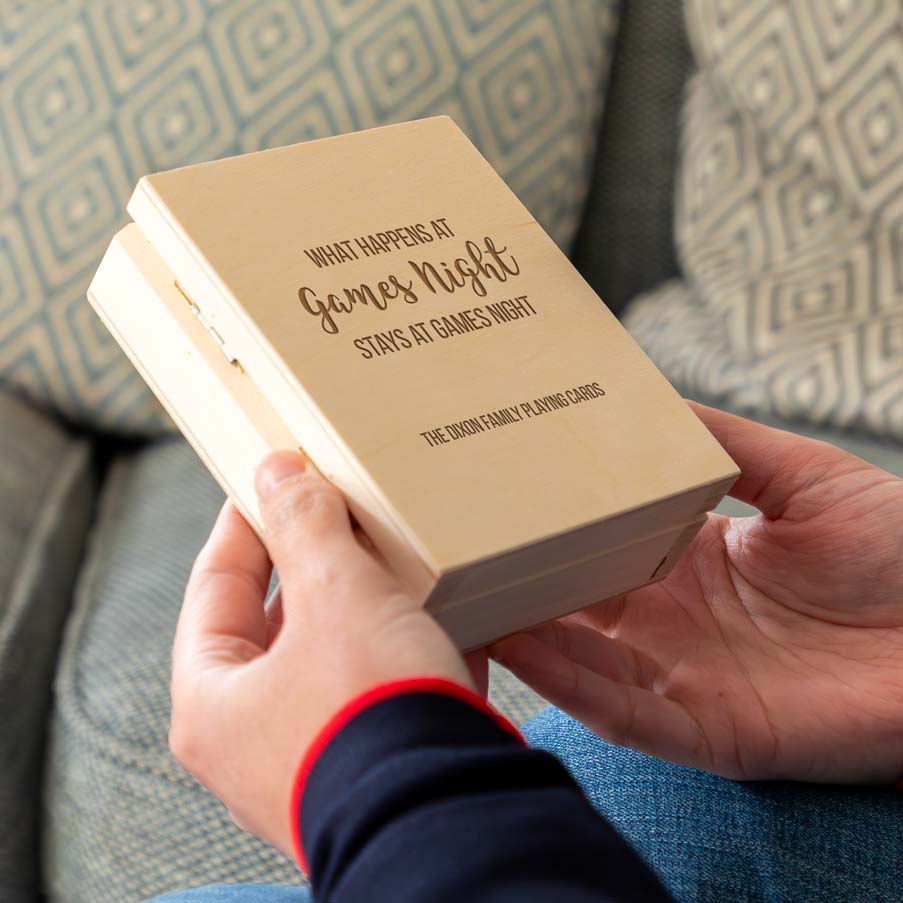 Person holding a wooden playing cards box engraved with 'what happens at games night stays at games night' with personalised text.