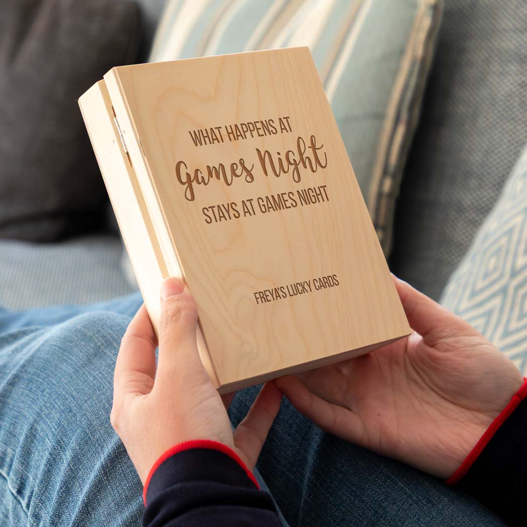 Wooden playing cards box engraved with 'What Happens at Games Night Stays at Games Night' held by a person.