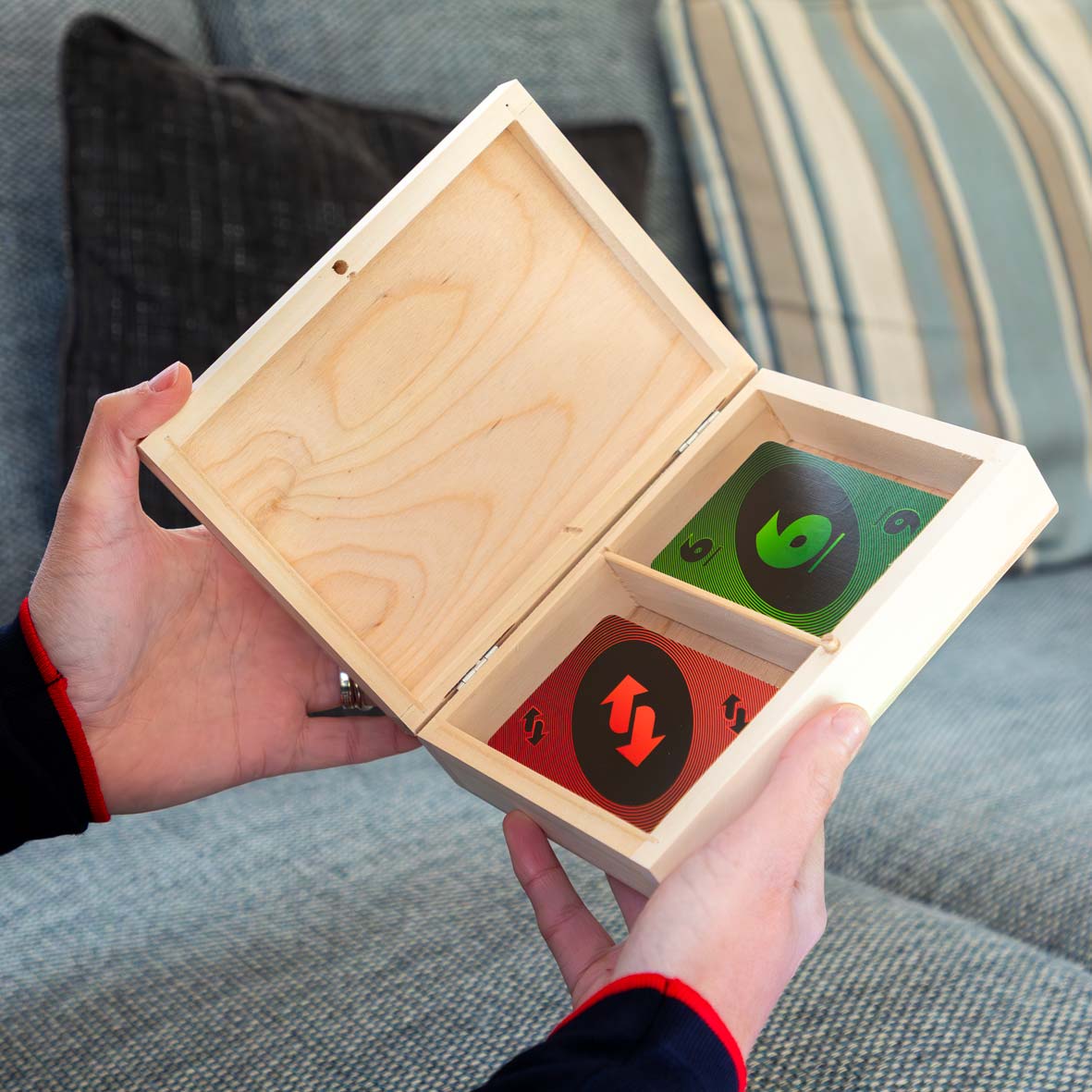 A person holding a wooden playing cards box open to show two packs of cards.