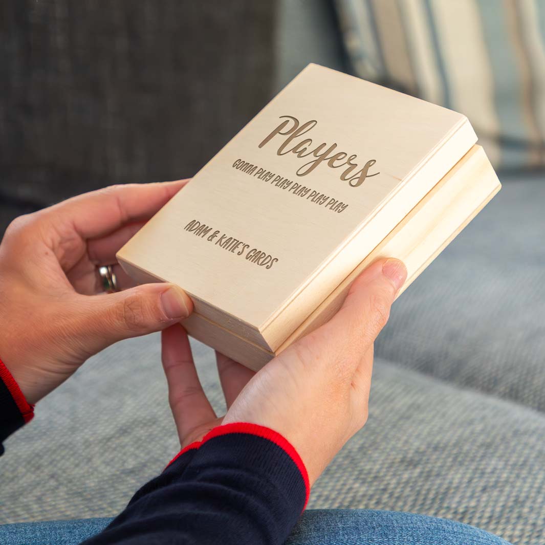 Person holding a wooden playing cards box engraved with 'Players gonna play' and personalised text.