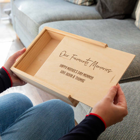 Wooden photo box engraved with 'Our Favourite Memories' and a personalised message held by a person, sitting on a couch.