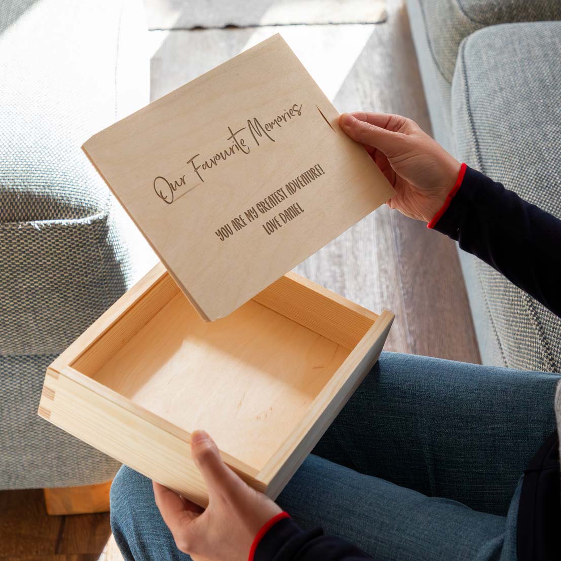 Person opening a wooden photo box with a personalised lid, engraved with 'Our Favourite Memories'.