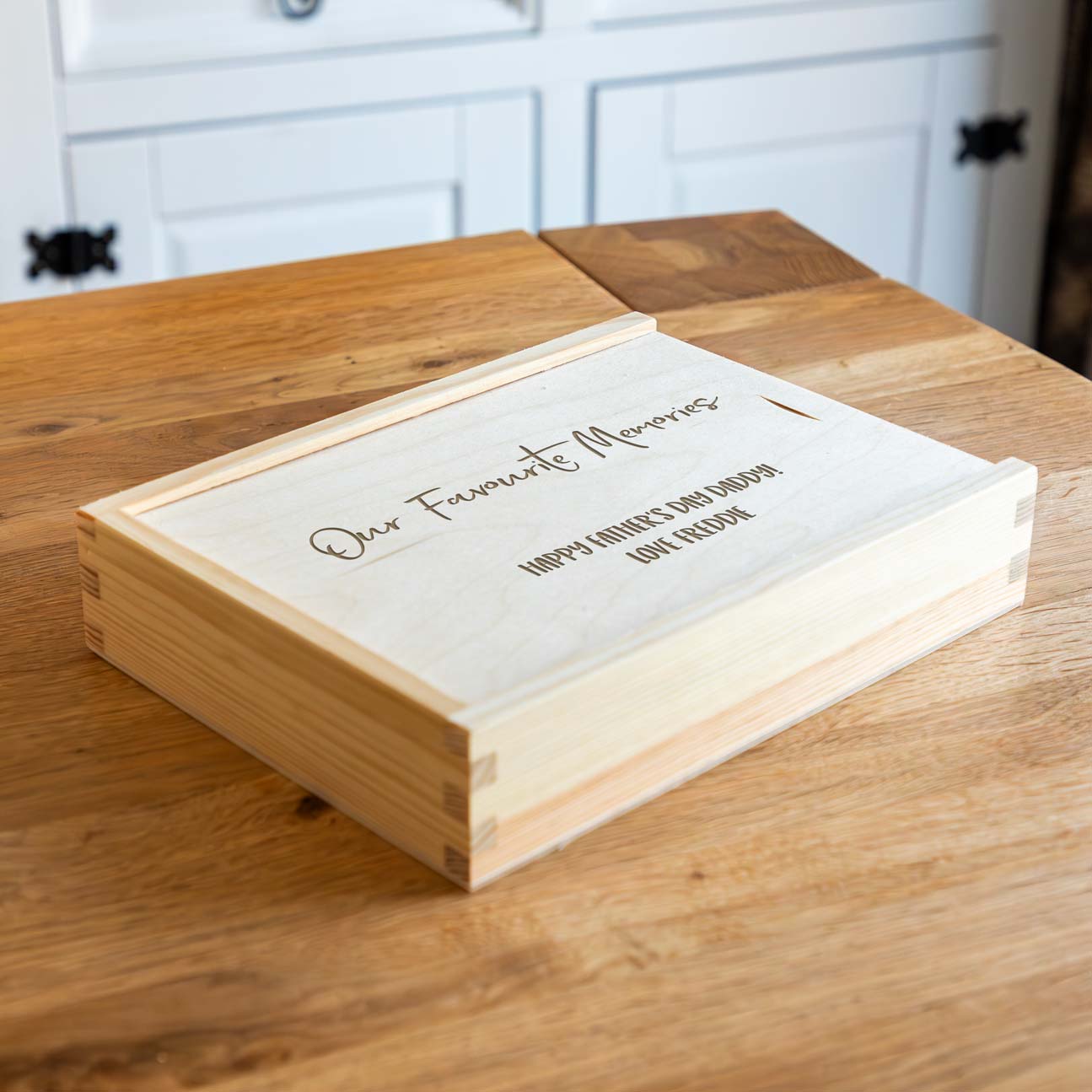 Wooden photo keepsake box with engraved personalised text on a wooden surface.