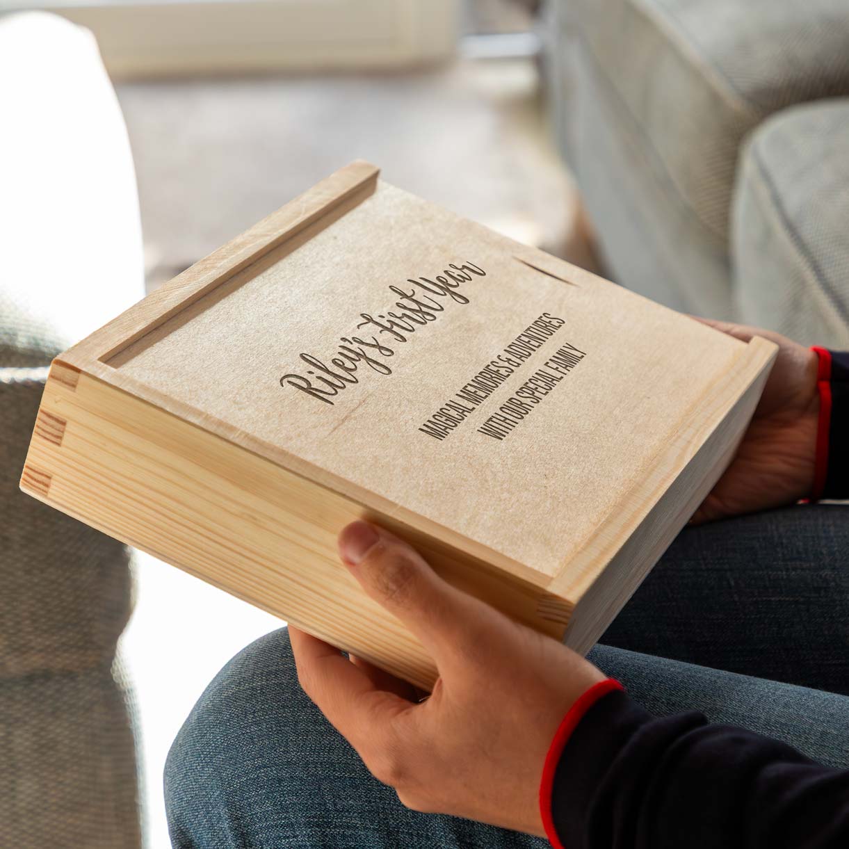 Person holding a wooden photo box with engraved text.