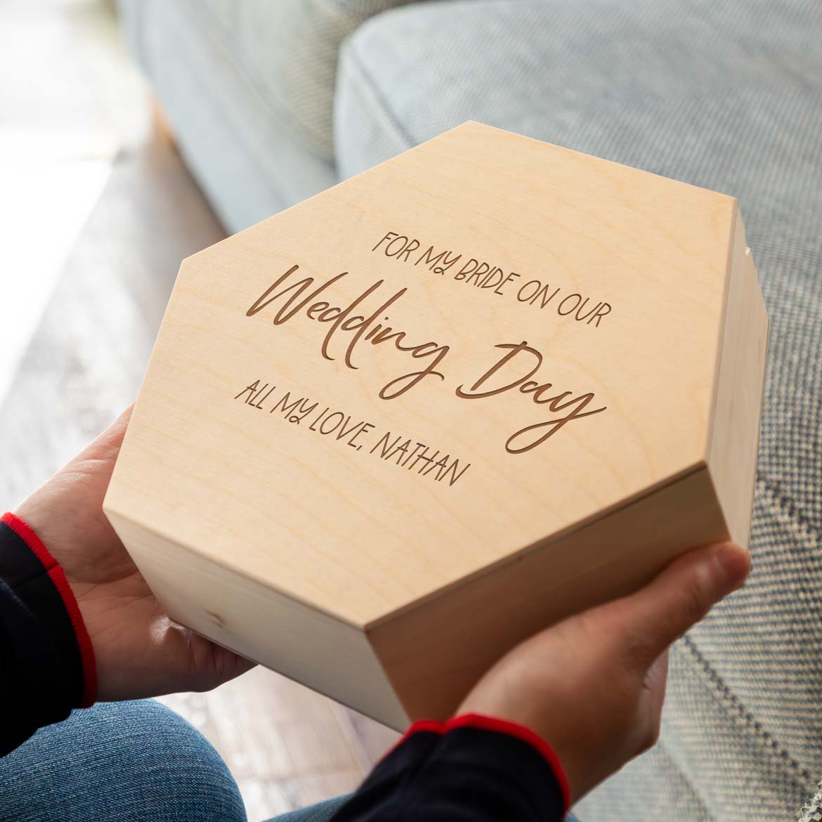 Hexagonal wooden keepsake box with personalised text held by a person, a gift from the groom to the bride on the wedding day.