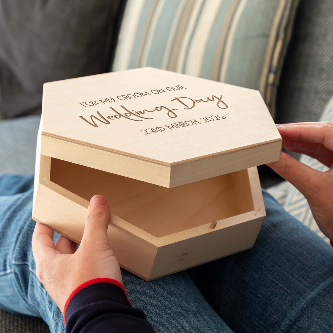 Hexagonal wooden keepsake box with personalised text held by a person, a gift from the bride to the groom on the wedding day.