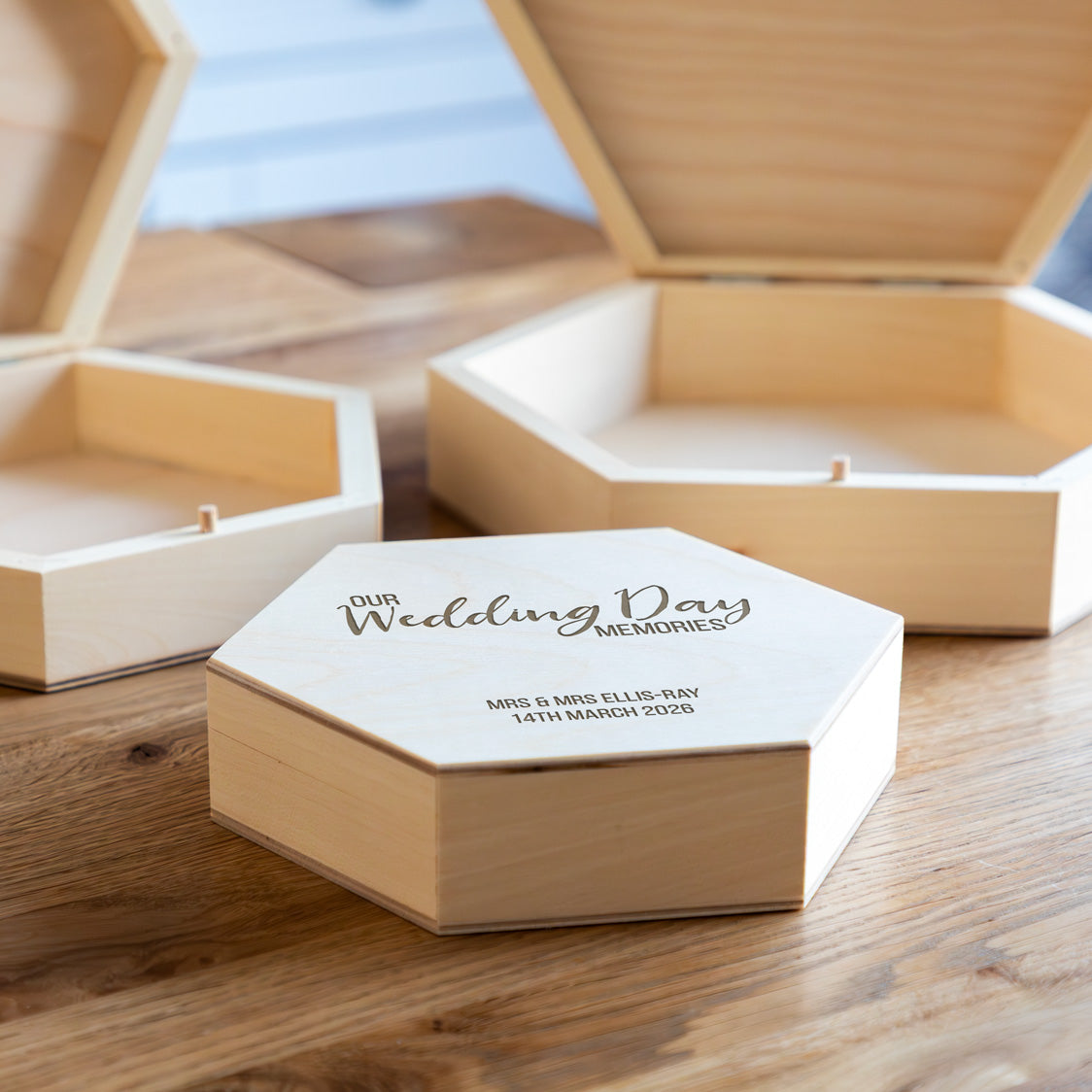 Wooden hexagonal wedding keepsake box with engraved personalised text on a wooden surface.