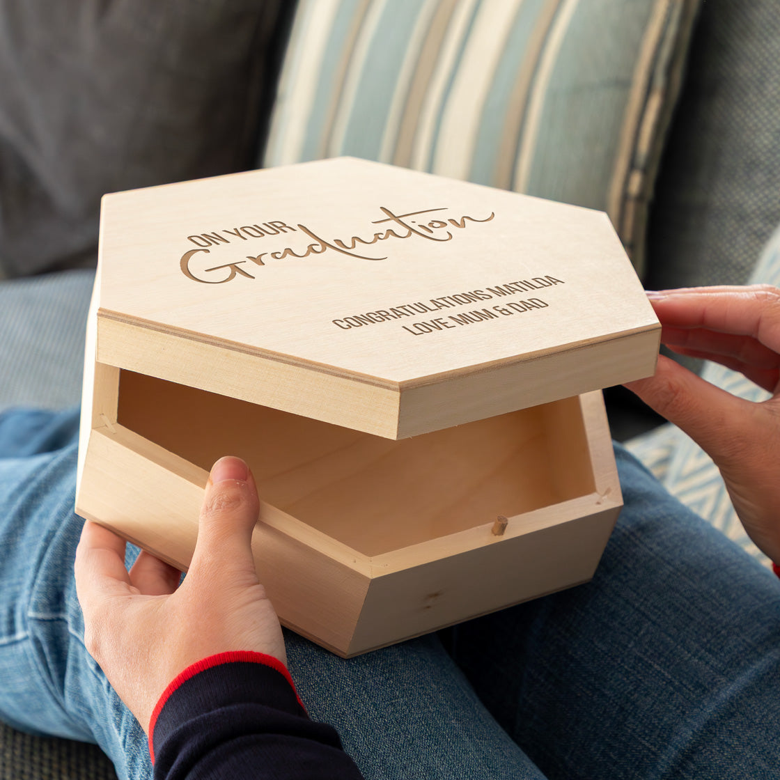 Wooden graduation keepsake box with engraved personalised text held by a person.