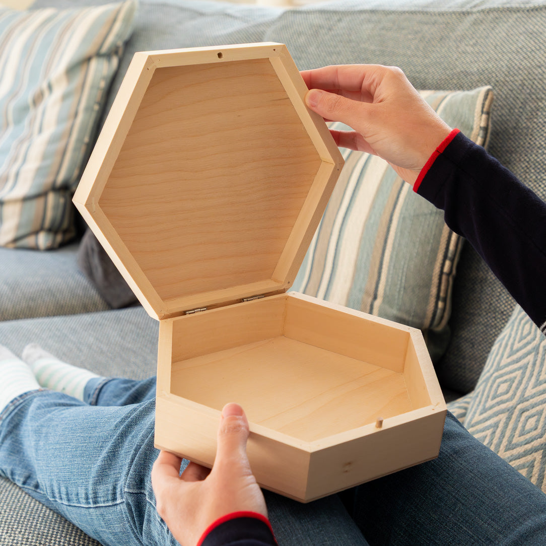 Person holding a hexagonal wooden keepsake box open.