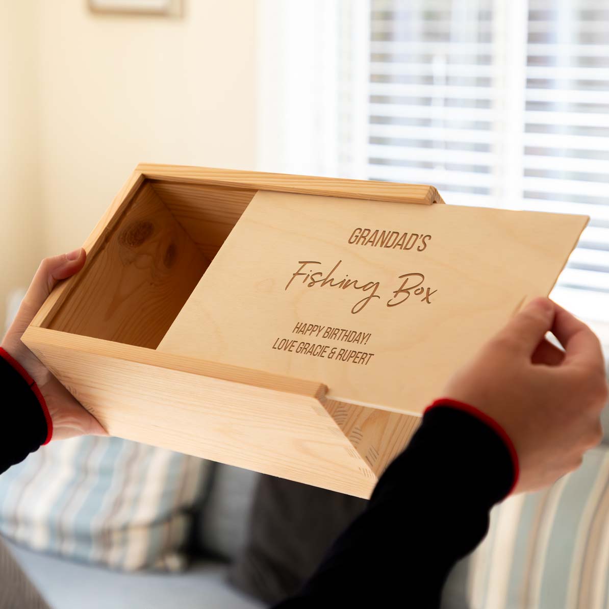 Wooden fishing storage box engraved with 'Grandad's Fishing Box' being held by a person.