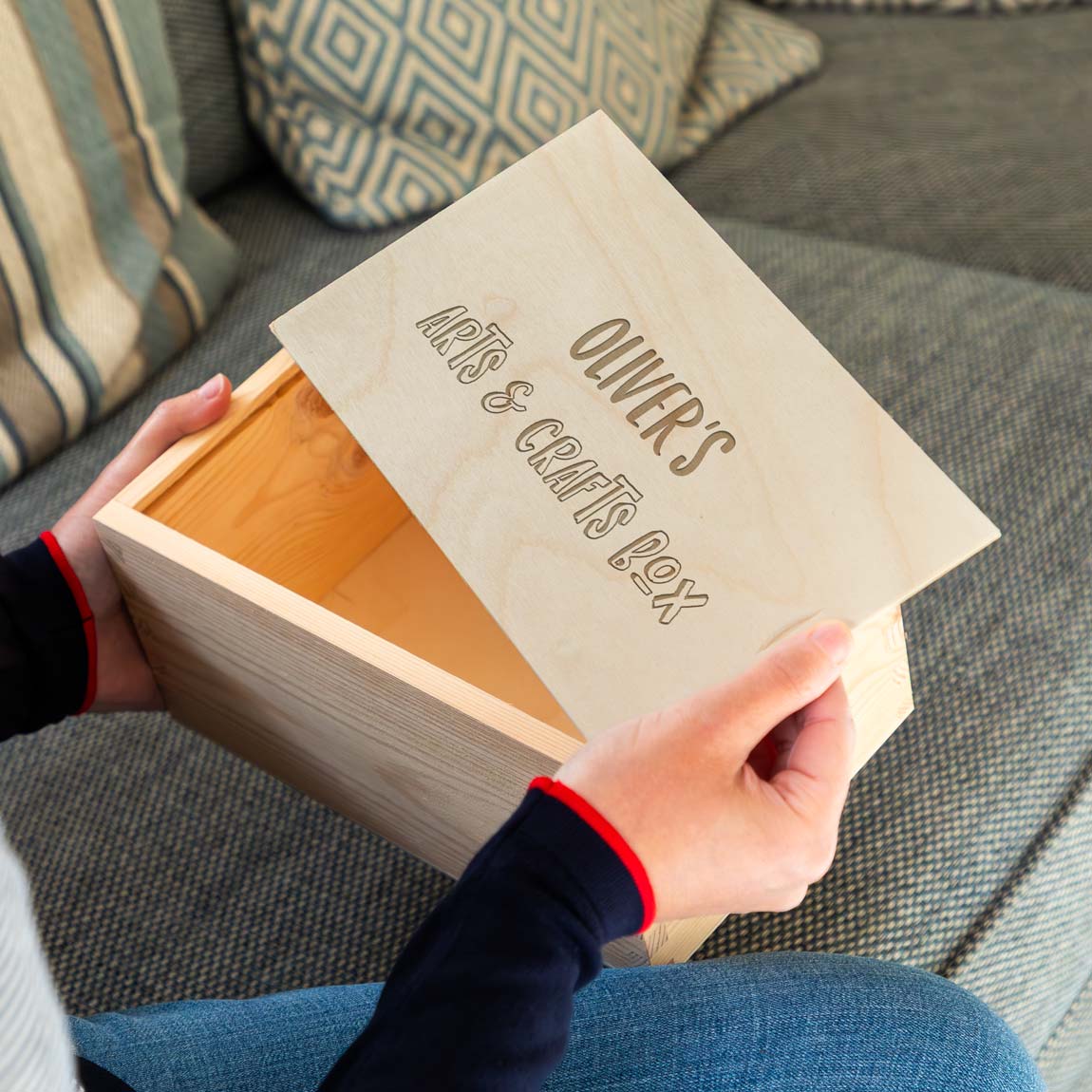 Wooden craft box engraved with the personalised name and 'Arts & Crafts Box' held by a person on a couch.