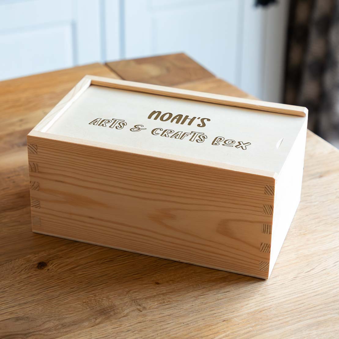 Wooden arts and crafts box laser engraved with a personalised name, on a wooden surface.