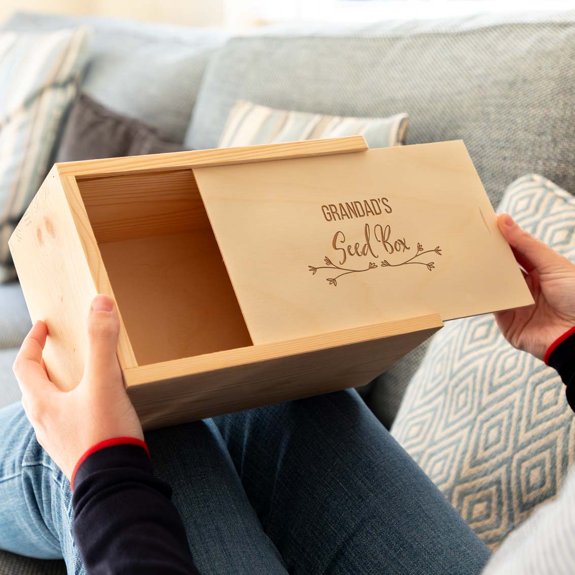 Wooden garden seed box engraved with the personalised name and 'Seed Box' held by a person on a couch.