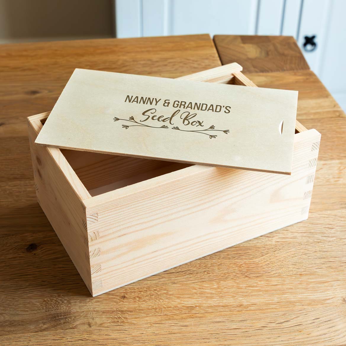 Wooden seed box with engraved personalised text on a wooden surface.