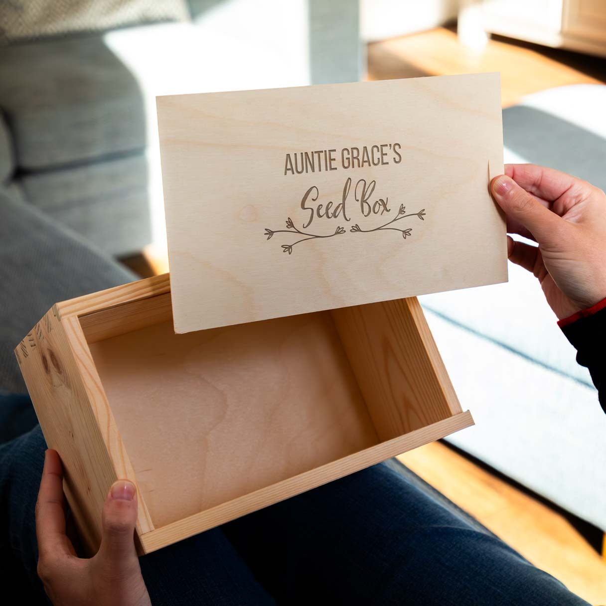 Wooden seed box with the lid engraved with 'Auntie Grace's Seed Box' held by a person.