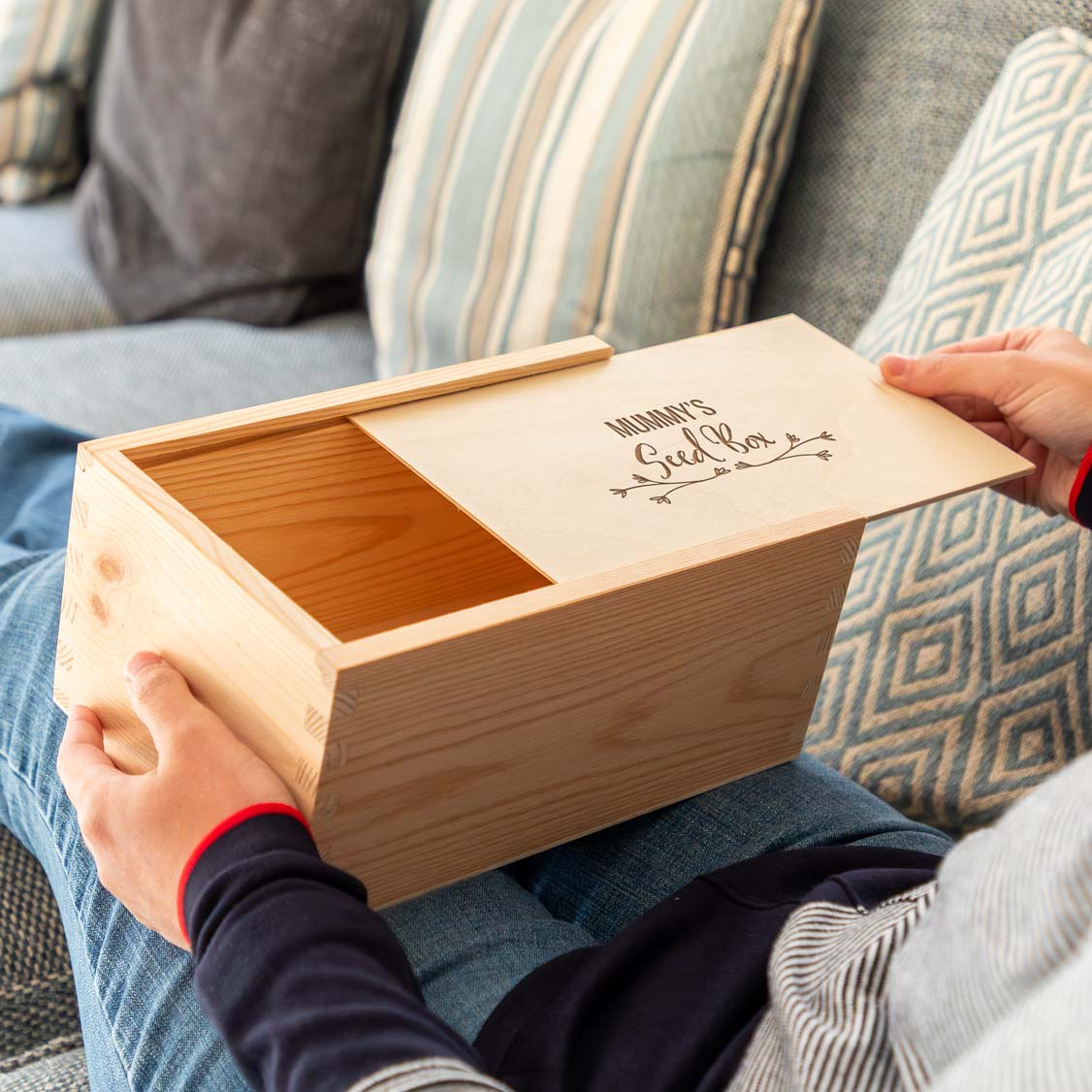 Wooden seed box engraved 'Mummy's Seed Box' held by a person on a couch.