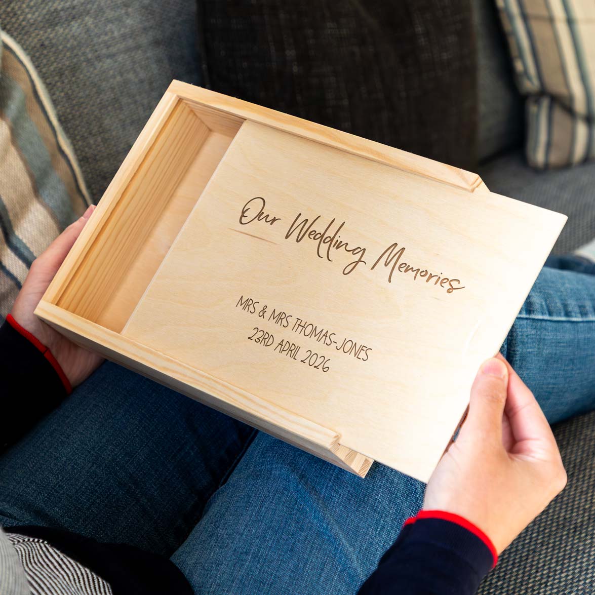 Wooden photo keepsake box with 'Our Wedding Memories' engraving held by a person.
