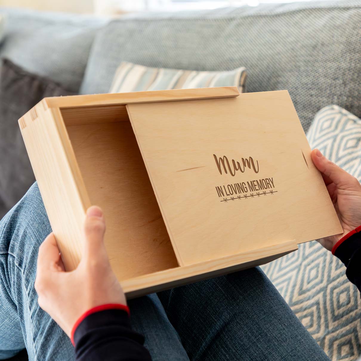 Wooden photo keepsake box with 'In Loving Memory' engraving held by a person on a couch.
