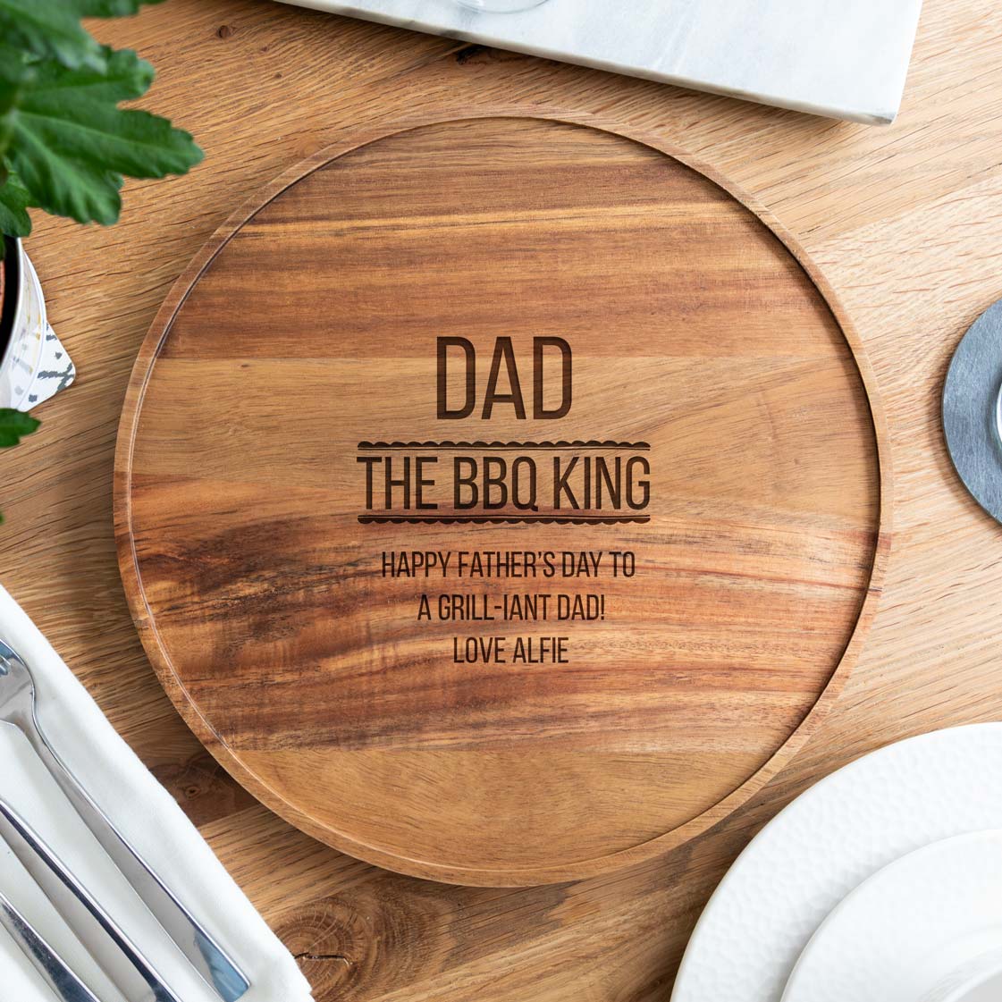 Wooden serving board engraved with 'The BBQ King' text and a special message for Father's Day on a wooden surface.