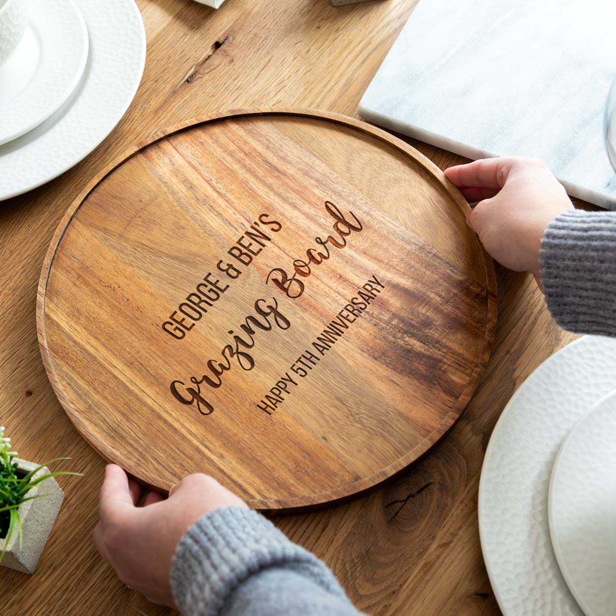 Wooden personalised grazing board with engraved text on a table setting.