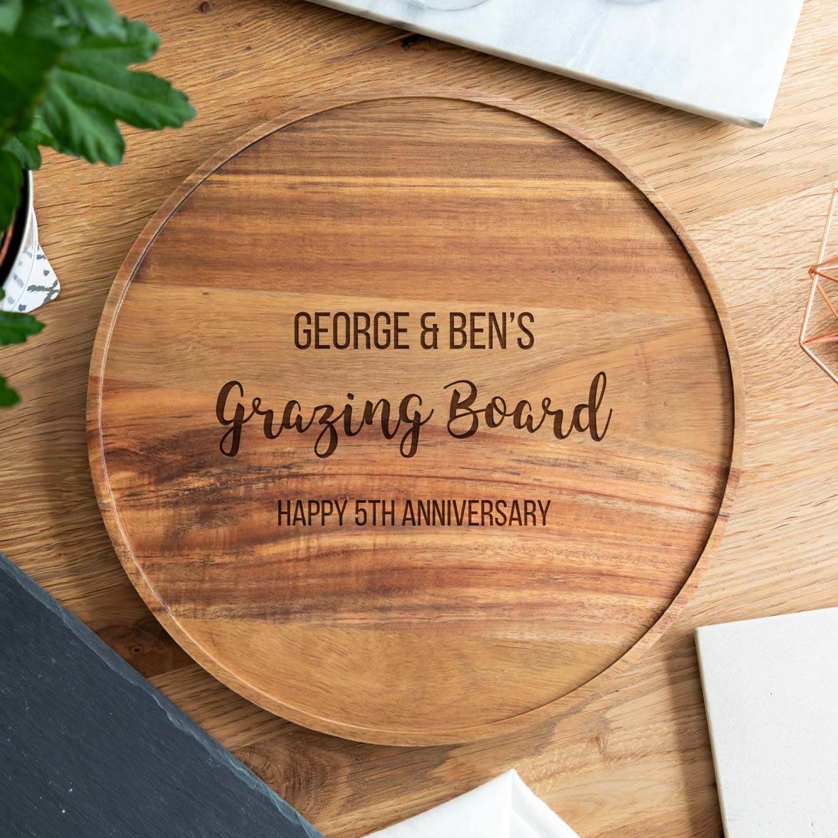 Wooden personalised grazing board with engraved text on a wooden surface.
