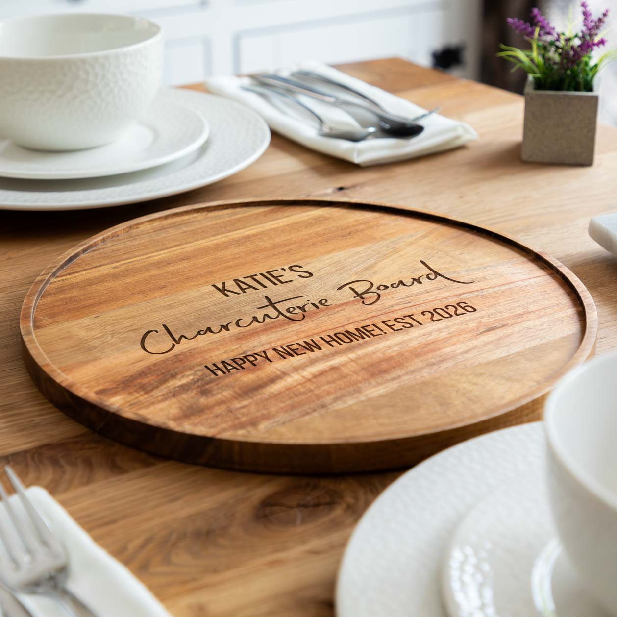 Wooden charcuterie board with engraved text on a dining table.