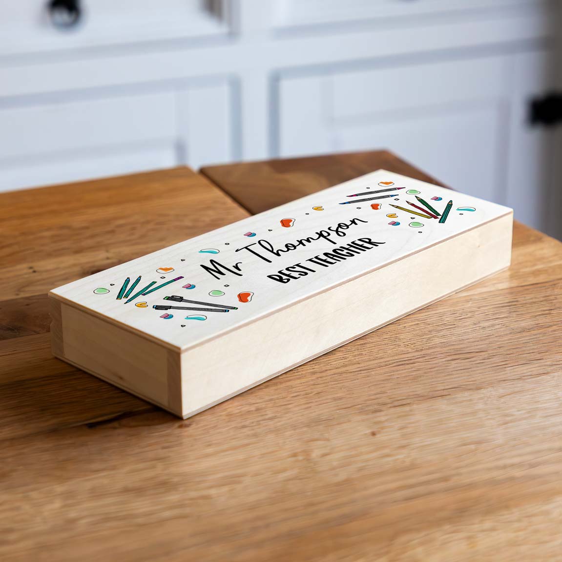 Wooden pencil case with colourful illustrations, personalised with the name and 'Best Teacher'.