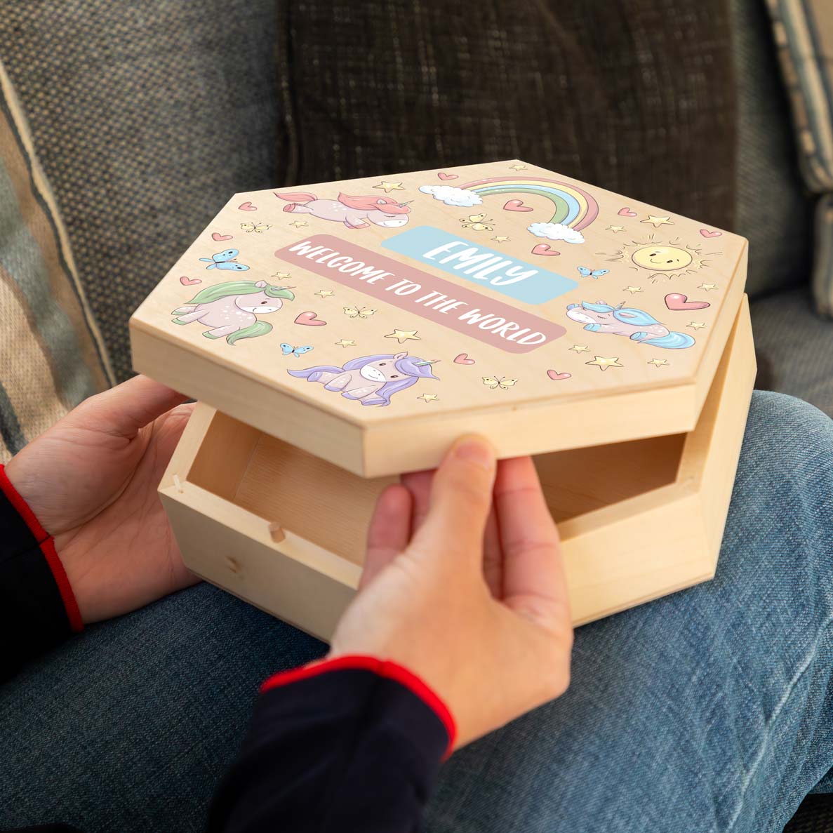 Wooden new baby memory box with colourful unicorn illustrations and personalised text, held by a person.