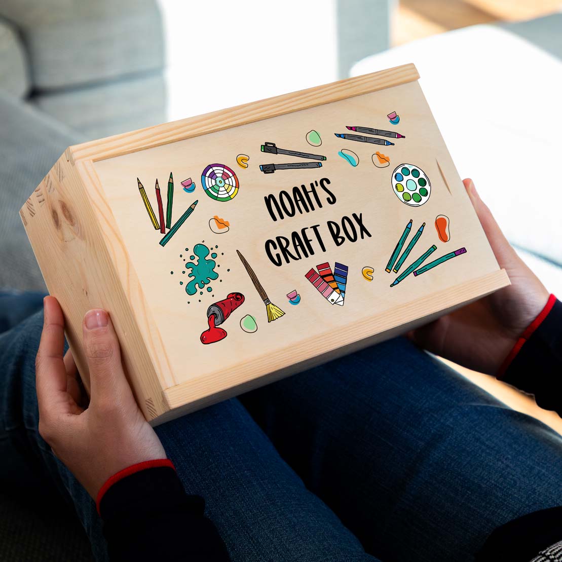 Wooden craft box with colourful illustrations and personalised text held by a person.