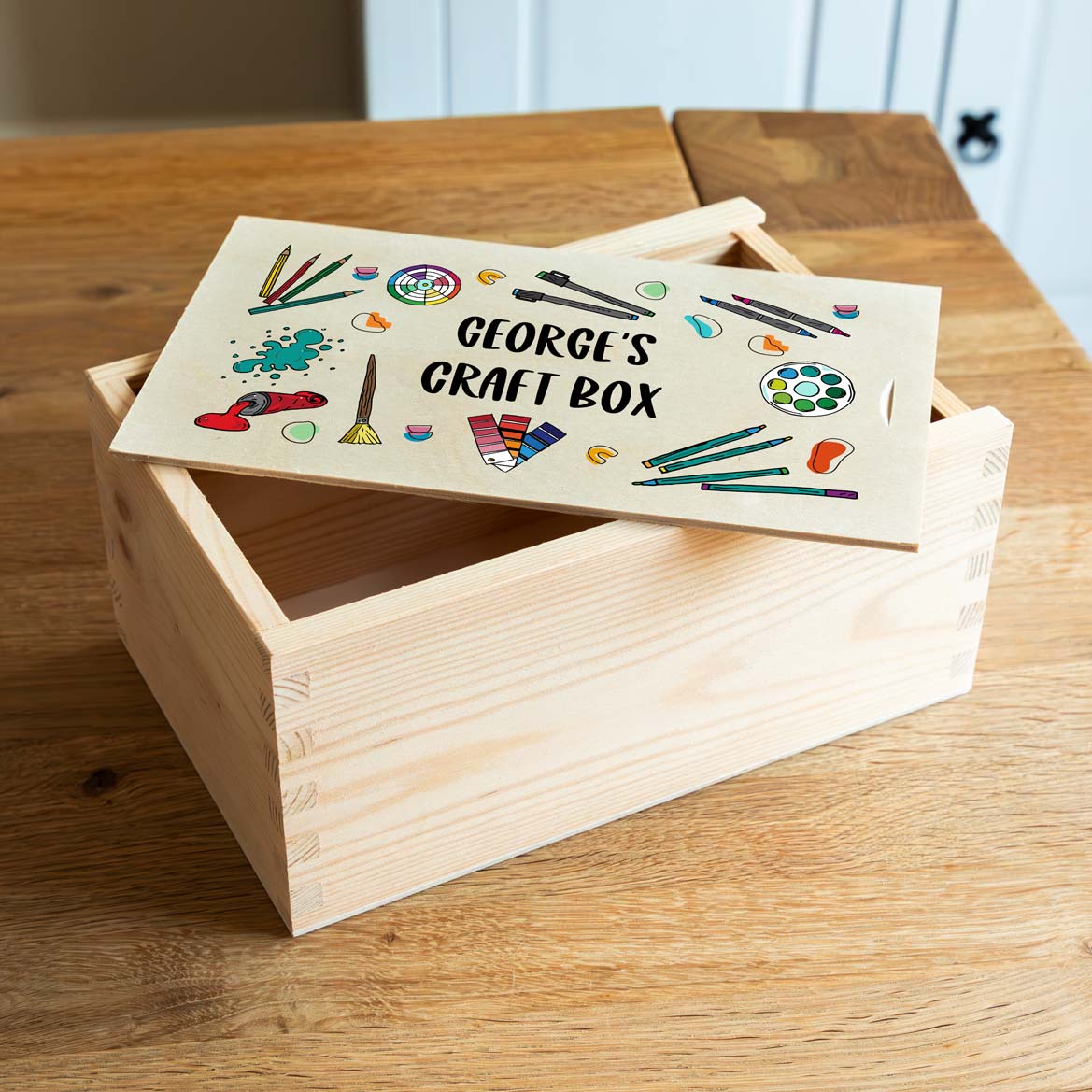 Wooden craft box with a personalised design printed on the lid, on a wooden surface.