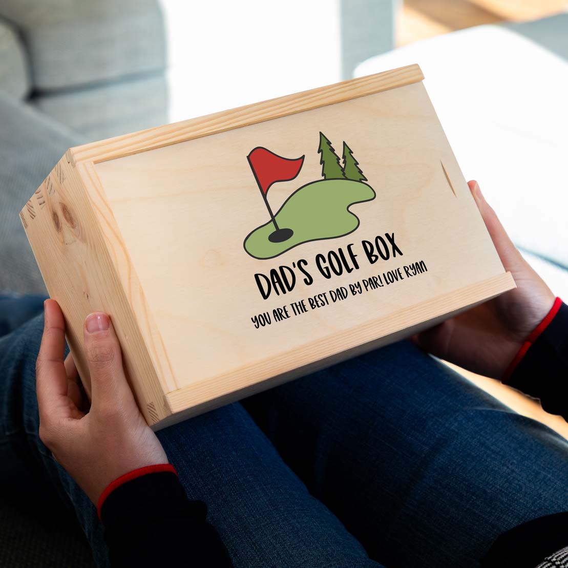 Wooden golf storage box with a personalised golf design and text held by a person, sitting on a couch.