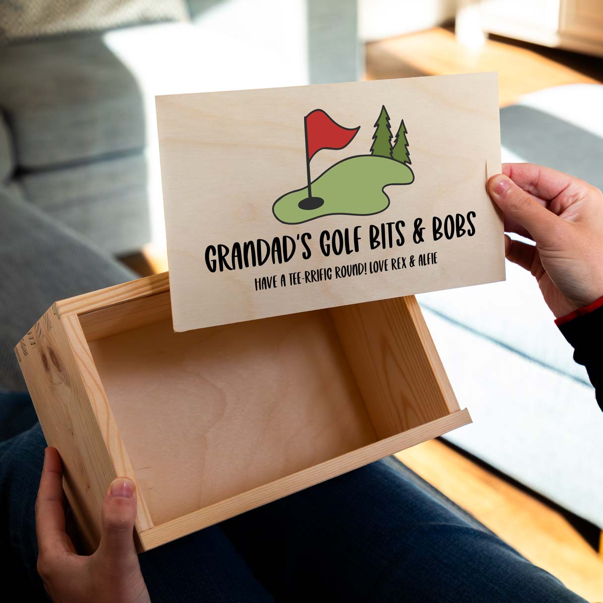 Wooden storage box with the sliding lid personalised with 'Grandad's Golf Bits & Bobs' held by a person.