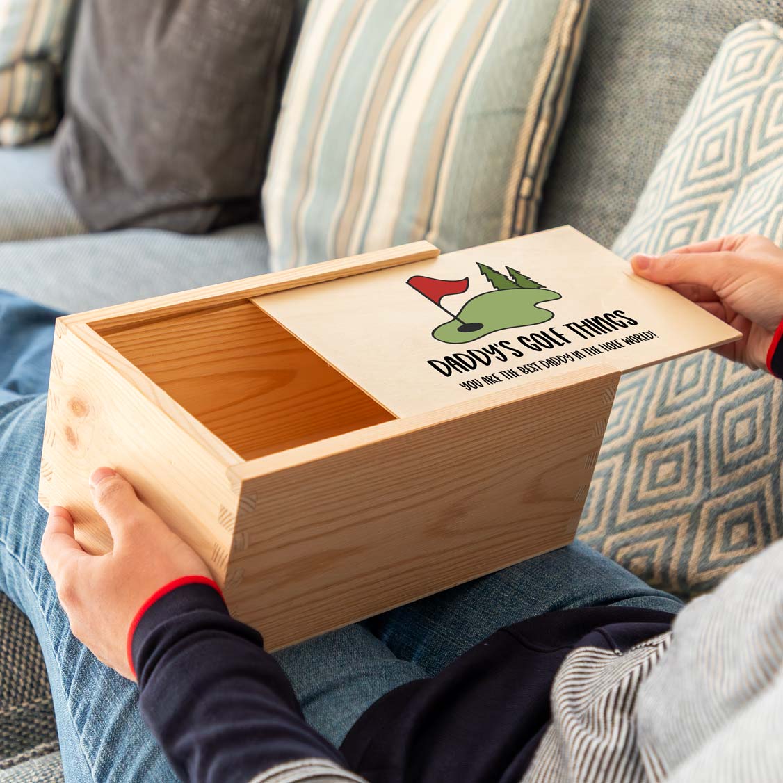 Wooden storage box with a sliding lid and a golf-themed personalised design held by a person on a couch.