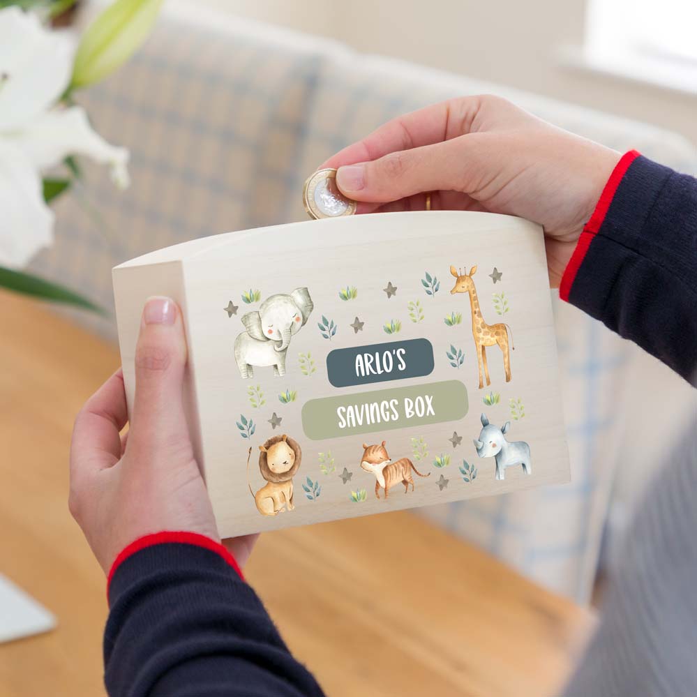 Person holding a personalised savings box with jungle animal design and personalised text.