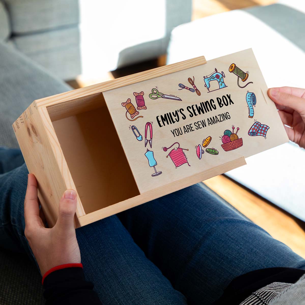 Wooden sewing box with colourful illustrations and personalised text held by a person.