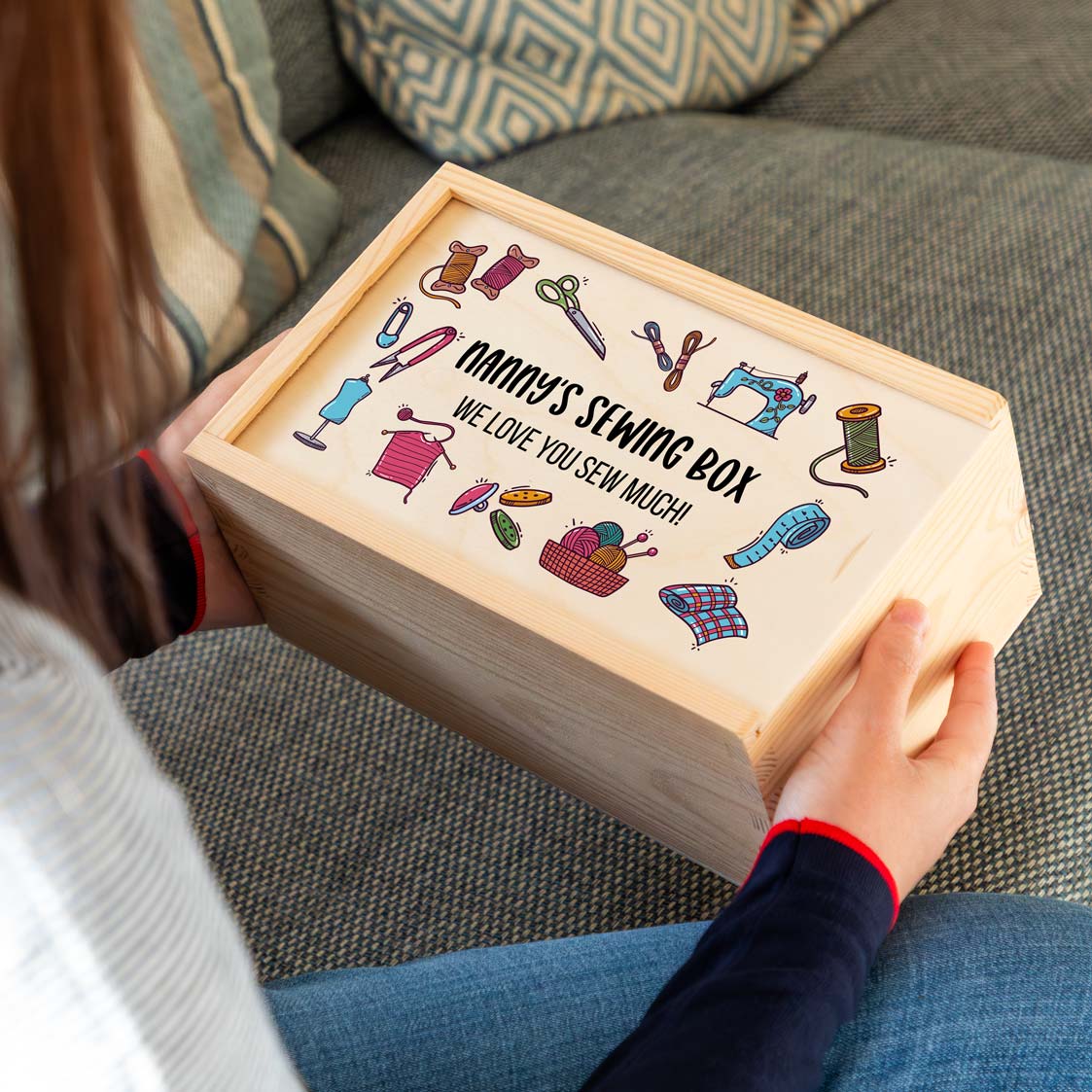 Wooden sewing box with sewing illustrations and personalised text held by a person.
