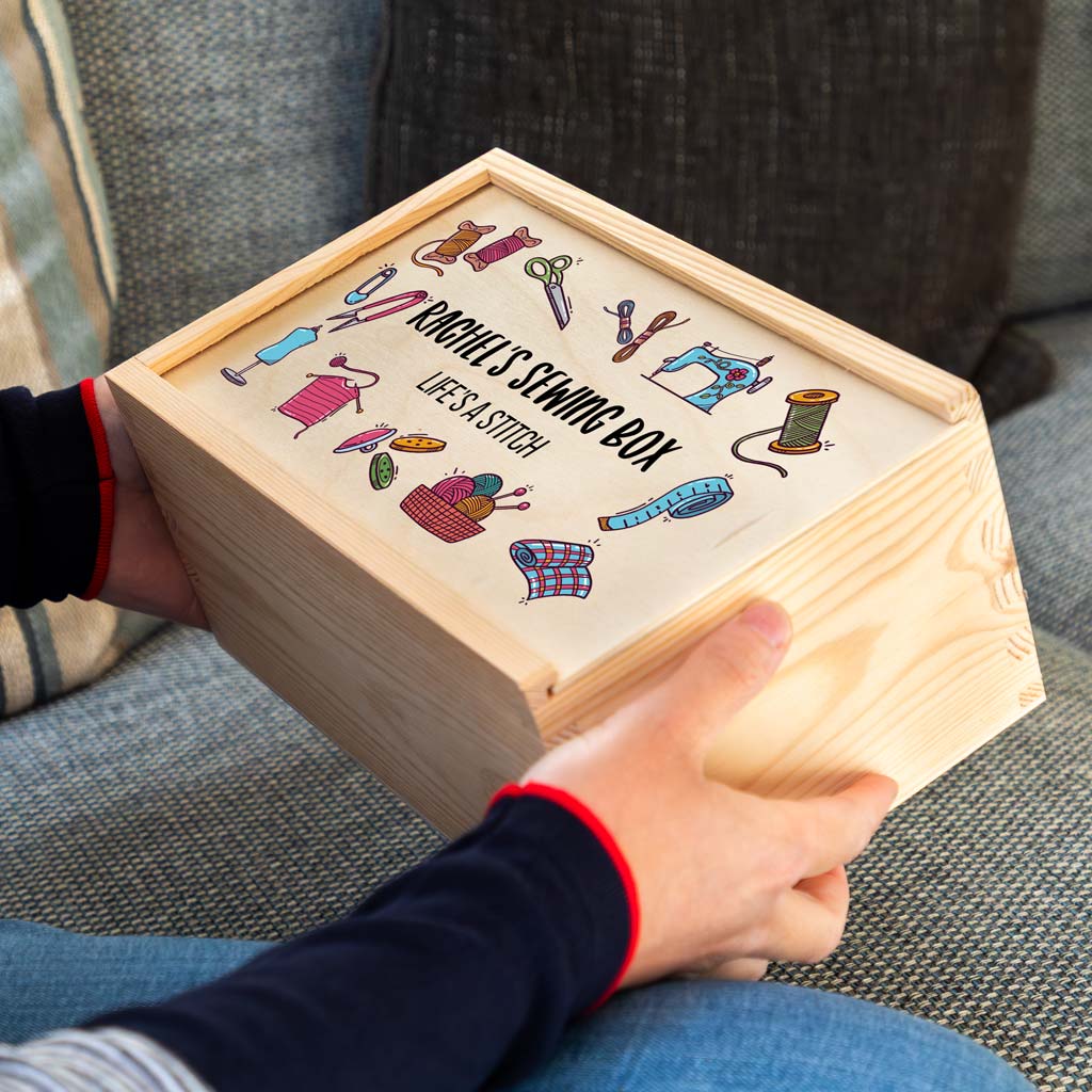 Wooden sewing box with colourful illustrations of sewing items and personalised text held by a person.