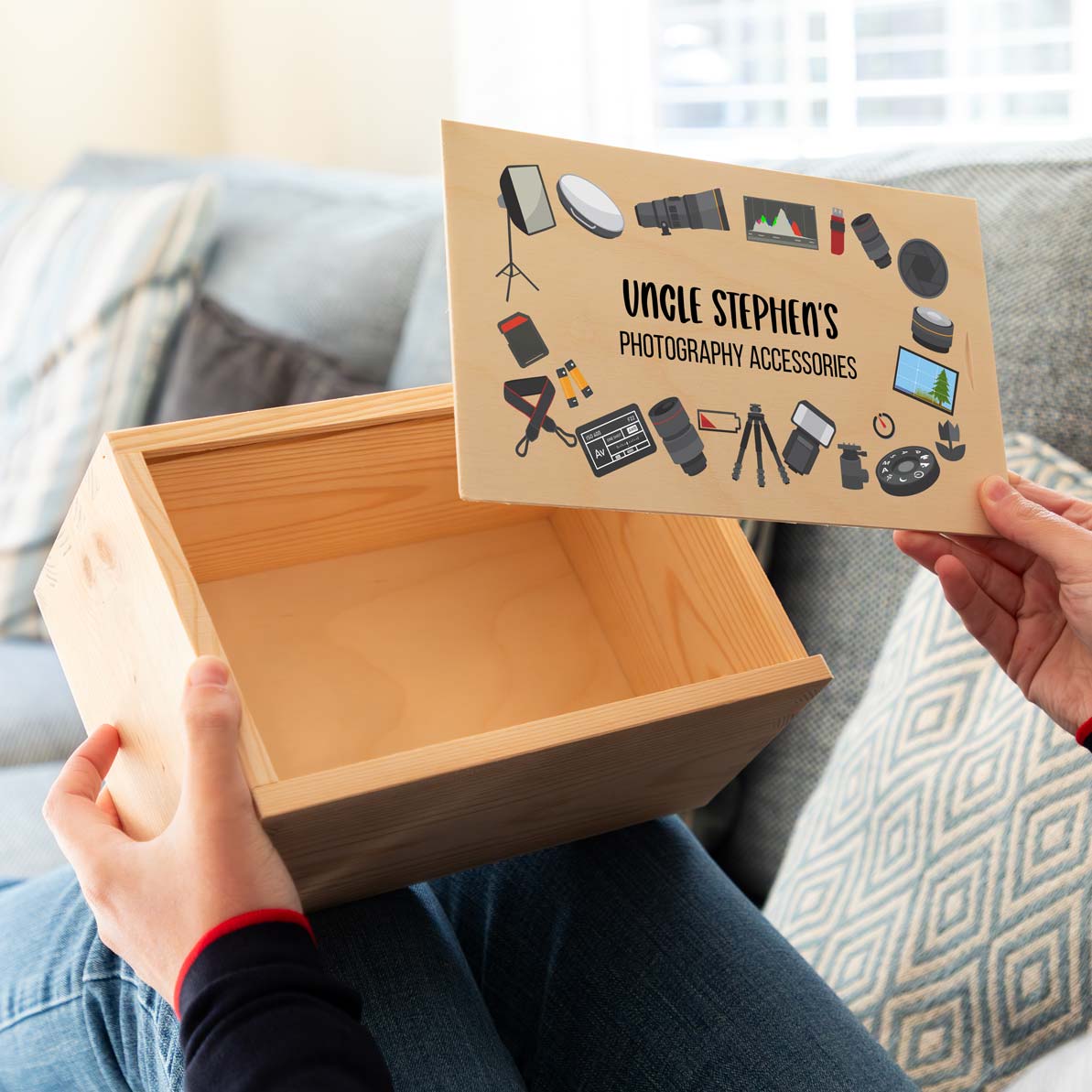 Person holding a wooden storage box for photography accessories with a personalised lid.