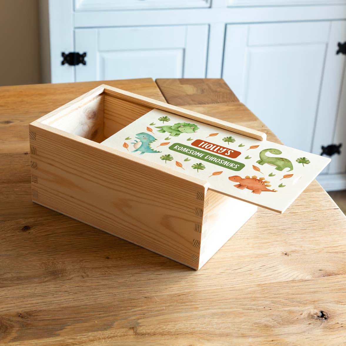 Wooden keepsake box with dinosaur-themed design on a wooden surface.