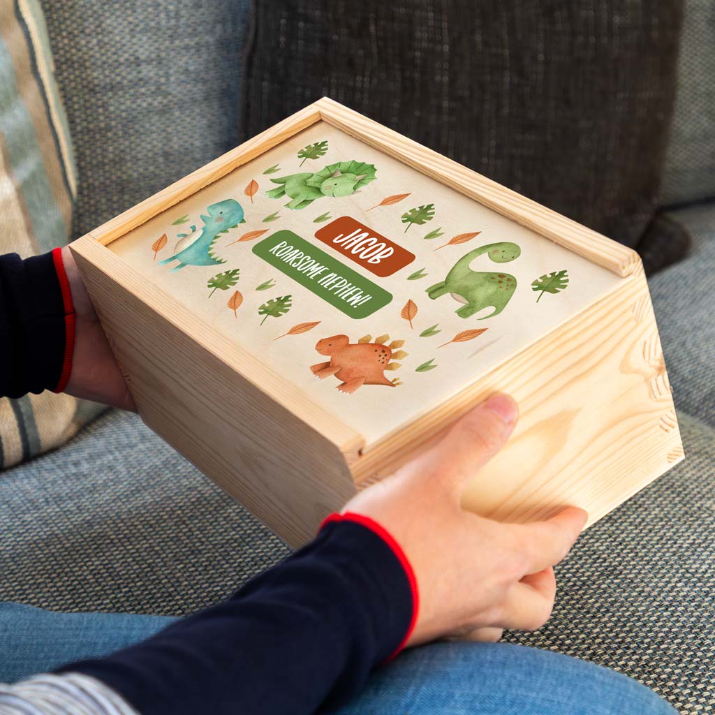 Wooden keepsake box with dinosaur illustrations and personalisation, held by a person