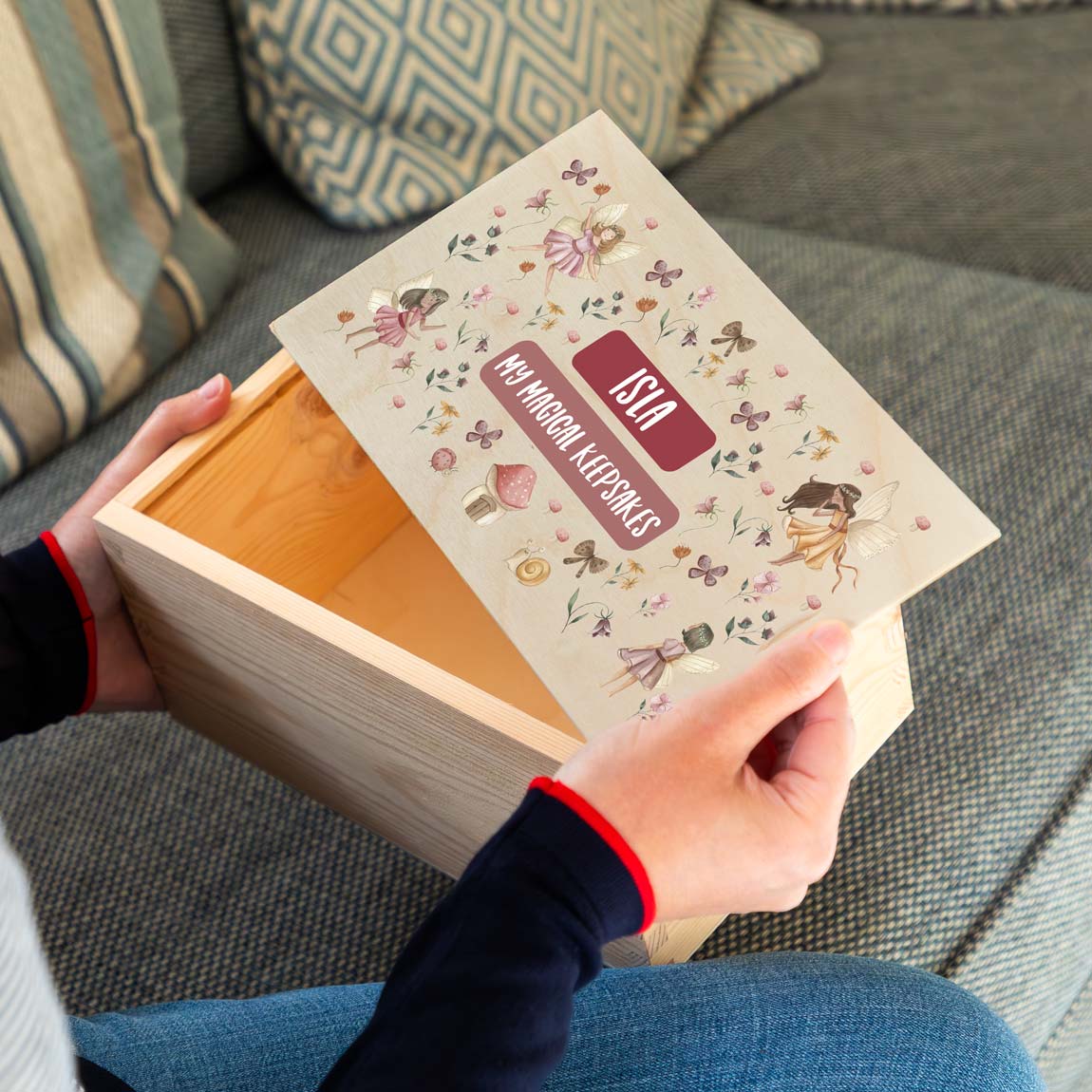 Person holding a wooden keepsake box with a decorative lid featuring fairy designs and personalised text.