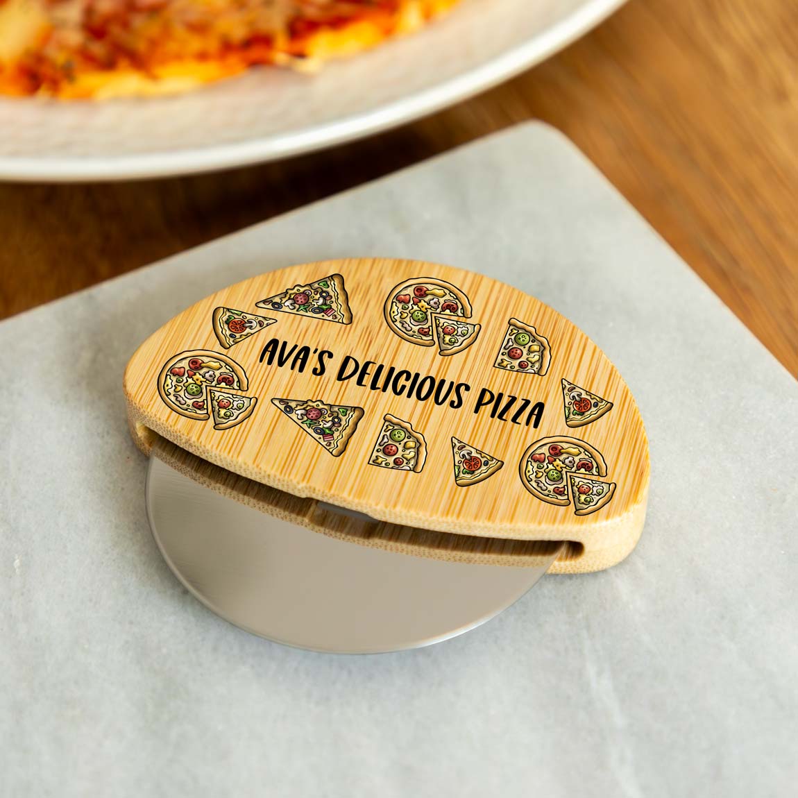 Wooden pizza cutter wheel with personalised text and pizza slice designs on a white surface.