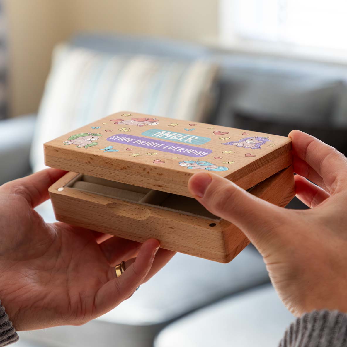 Hands opening a wooden unicorn jewellery box personalised with custom text.