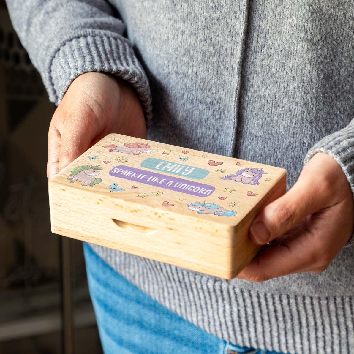 Wooden unicorn jewellery box personalised with any text, held in two hands.